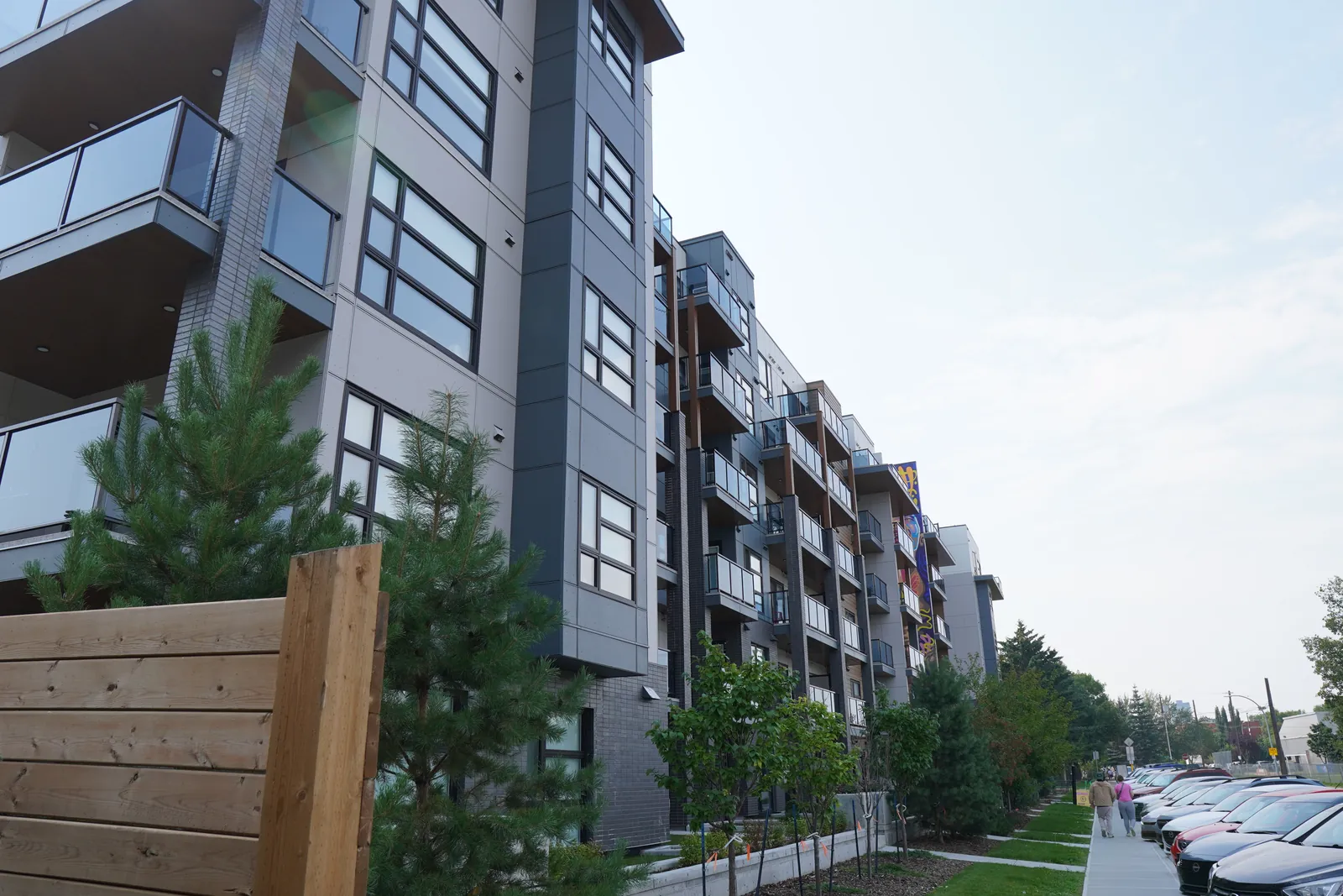 long side of a grey multifamily block, parked cars