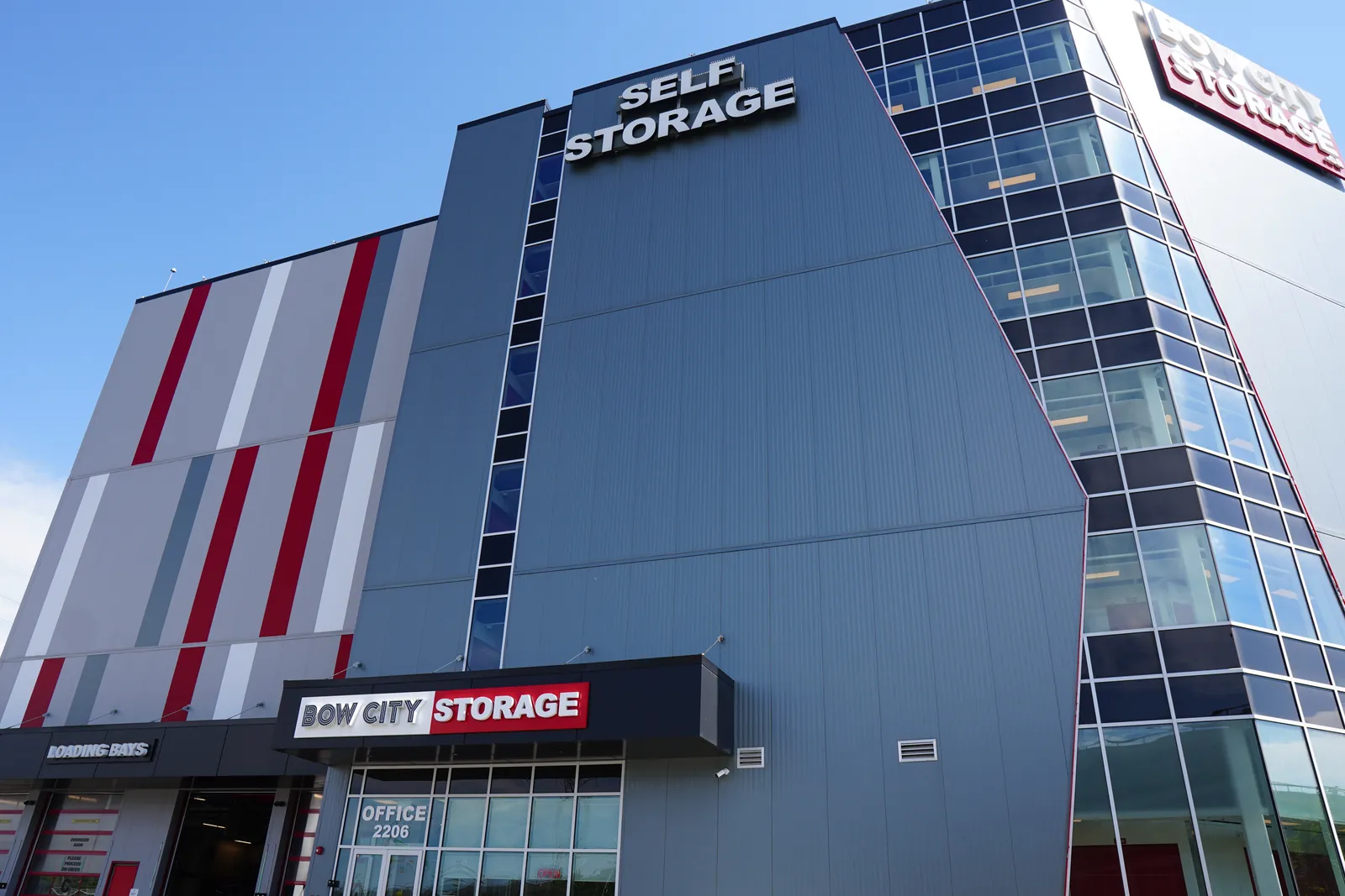 self-storage building, grey/red panels, glass tower corner, low angle