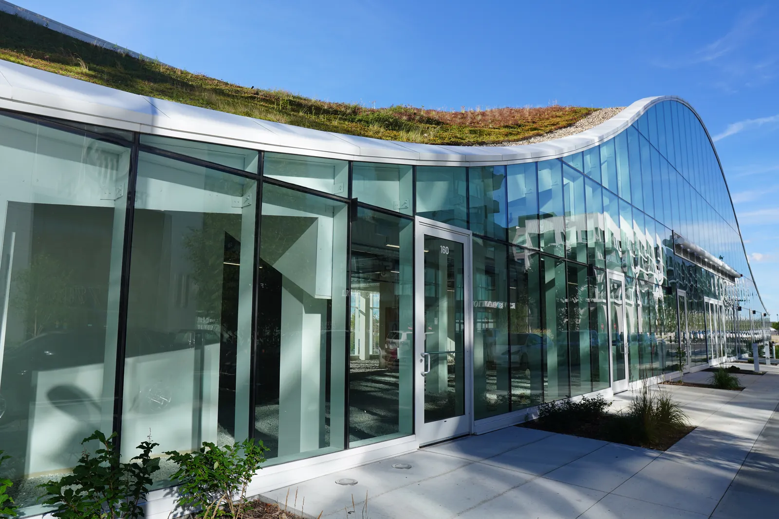 curved glass pavilion with green roof, strong low angle