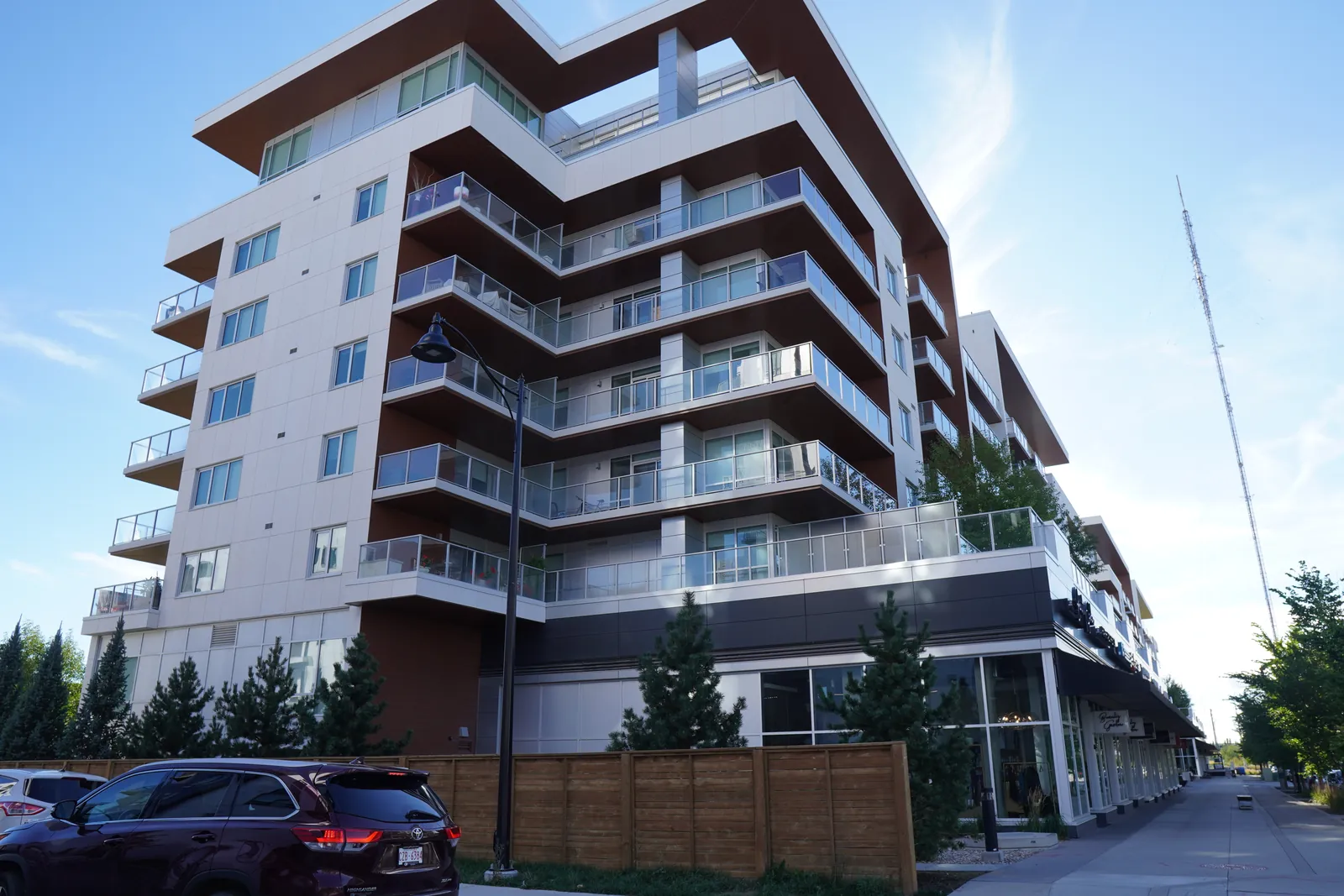 white and wood 8-storey corner, fence, car at edge
